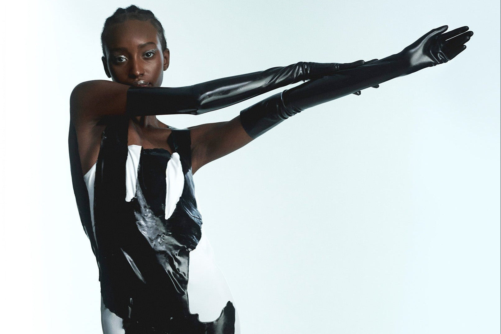 Person wearing a black and white dress with long gloves on a white background